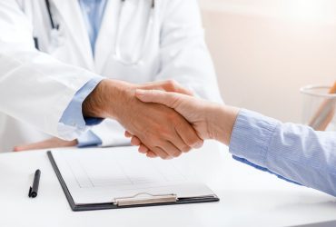 Senior female patient shaking hands with doctor